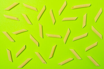Tubes of penne type of pasta on green background.