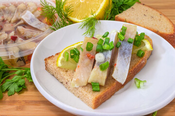 Open sandwich with pickled herring slices against ingredients, close-up