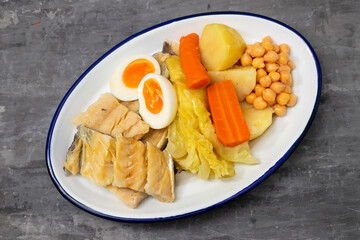 boiled cod fish with boiled vegetables and egg on white dish