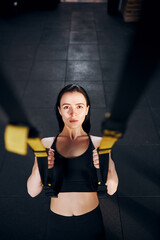 Determined female doing pull ups with straps