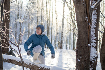 Girl jumping on a tree in the forest Outdoor activity. Walk in the forest in winter
