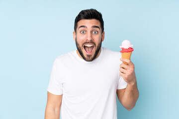 Caucasian man with a cornet ice cream isolated on blue background with surprise and shocked facial expression