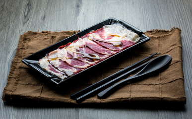 fresh raw pork, meat ,beef, belly, sliced on square plate  on fabric and wood, wooden background, shabu, hot pot ingredients.