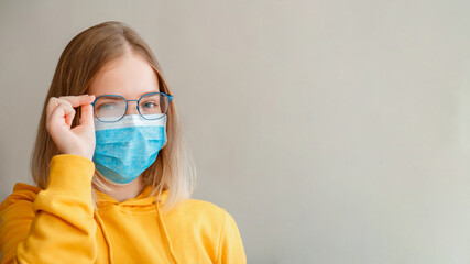 Foggy glasses wearing on young woman. Teenager girl in blue medical protective face mask and...
