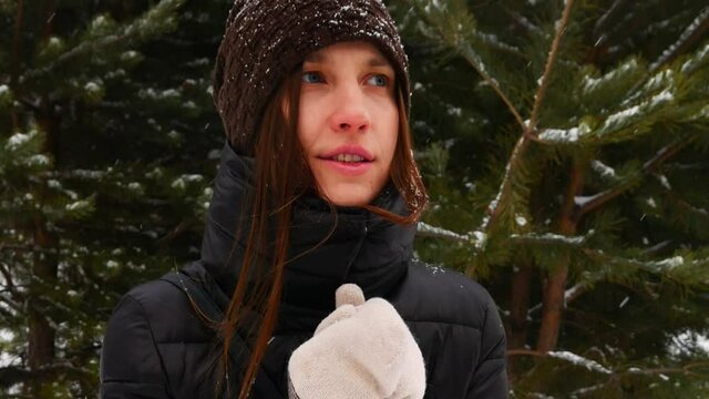 A young lady stands outdoors in winter and she is very cold
