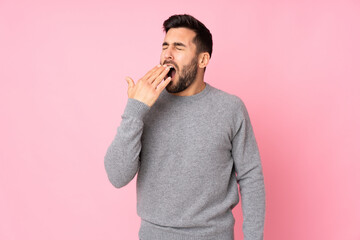 Caucasian handsome man over isolated background yawning and covering wide open mouth with hand