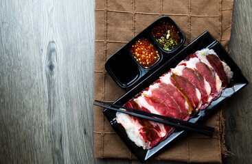 fresh raw pork, meat ,beef, belly, sliced on square plate  on fabric and wood, wooden background, shabu, hot pot ingredients.