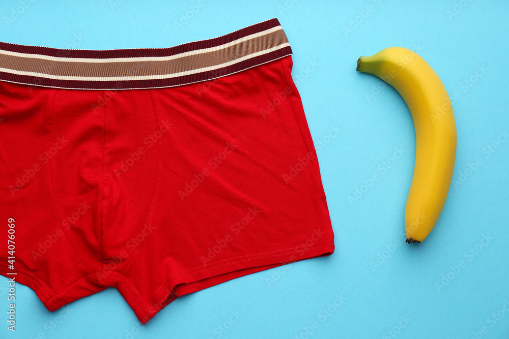 Wall mural Men's underwear and banana on light blue background, flat lay. Potency problem concept