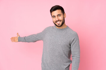 Caucasian handsome man over isolated background extending hands to the side for inviting to come - obrazy, fototapety, plakaty