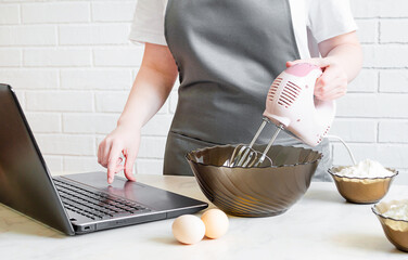 woman in an apron prepares food and searches for a recipe on the internet. online cooking training