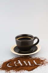 Black coffee in a cup with saucer with chill sign in ground coffee beans