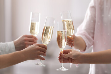 People clinking glasses of champagne against blurred background, closeup