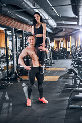 Obraz na płótnie Canvas Happy topless bodybuilder lifting girlfriend in gym