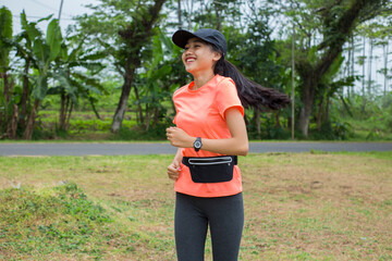 A portrait of a young asian woman doing excercise outdoor in a park, jogging
