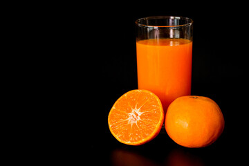 Oranges and Fresh Orange juice ready to drink. Isolated on black background.