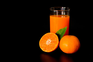 Oranges and Fresh Orange juice ready to drink. Isolated on black background.