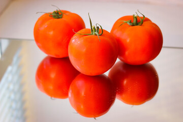 Several red tomatoes on a mirror surface