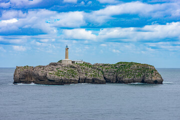 close view of a rock islet in the sea with a lighthouse