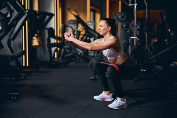 Fototapeta na wymiar Happy young woman doing squats in gym