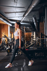 Fototapeta na wymiar Merry young woman spending active time in gym