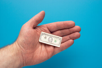 Toy tiny hundred dollar bill in open palm of a man, financial concept