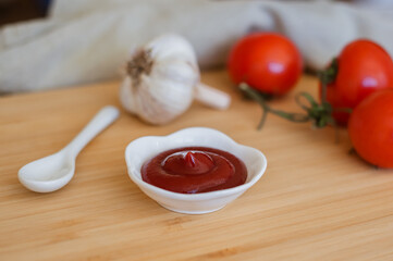 Ketchup or tomato sauce in a bowl, whole tomatoes, garlic close-up