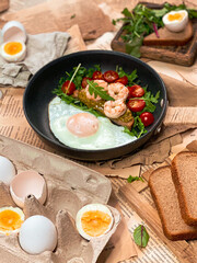 Fried eggs with shrimps, tomatoes and rocket salad