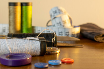 sewing trims. spool of thread, needle, buttons, scissors and measuring tape. Selective focus
