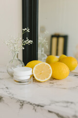 Cream with lemons on the marble fireplace. Self-care concept, cosmetology.