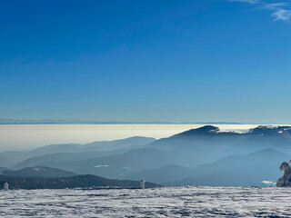 View of a distant mountain range (the Alps) from other snow-capped mountains (the Vosges) with a sea of clouds