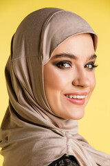 Close up. Beautiful young arab woman in stylish hijab isolated on yellow studio background with copyspace for ad. Fashion, beauty, style concept. Female model with trendy make up, manicure accessories