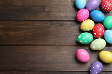 Colorful eggs on wooden background, flat lay with space for text. Happy Easter