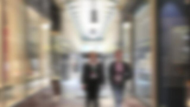 Abstract blurred couple walking towards the camera through a narrow shopping arcade