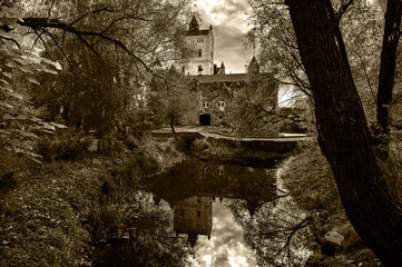 old castle in the forest with lake in black and white sepia 