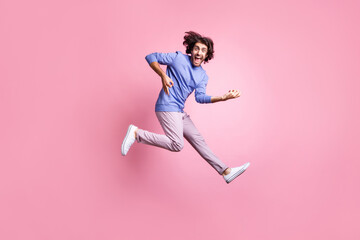 Fototapeta na wymiar Full size photo of young positive handsome crazy excited smiling man jump play invisible guitar isolated on pink color background