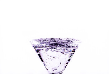 Close-up of water drop falling into a glass on white background