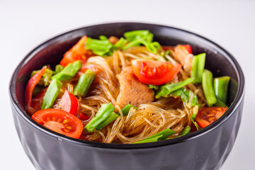 delicious glass noodles with chicken and vegetables on a white acrylic background