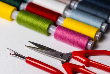 Spools with multi-colored threads and scissors on a light background. Sewing and handicraft accessories