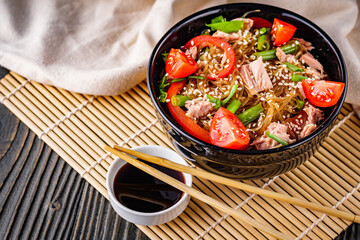 delicious glass noodles with tuna and vegetables on a dark wooden rustic background