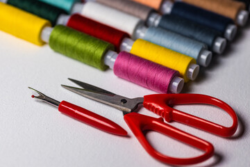 Spools with multi-colored threads and scissors on a light background. Sewing and handicraft accessories
