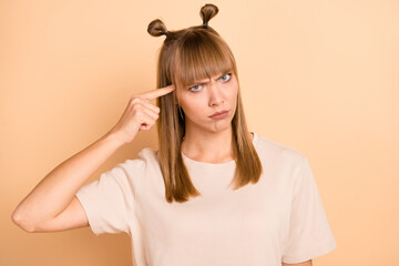 Photo portrait of unhappy girl keeping finger near forehead bad attitude isolated on pastel beige...