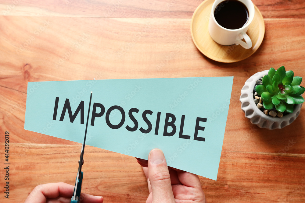 Poster man hand holding card with the text impossible, cutting the word im so it written possible. success 