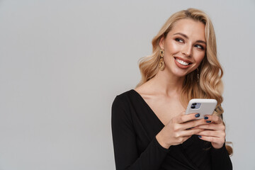Happy girl in luxury earrings smiling while using mobile phone