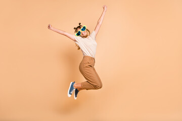 Fototapeta na wymiar Full body photo of young excited girl happy positive smile jump up celebrate victory fists hands isolated over beige color background