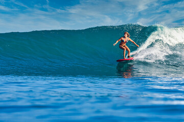 Female surfer on a blue wave at sunny day