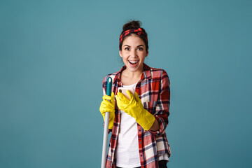 Excited beautiful girl in gloves with mop using mobile phone
