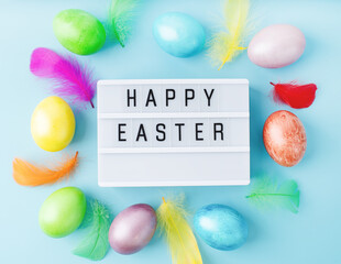Top view Happy Easter light box decorated with bright colored eggs and feathers
