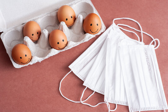 Easter 2021. Happy Easter to the Coronavirus. Brown Easter eggs and white medical face masks on a brown background.