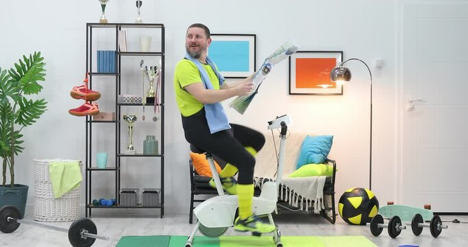 funy man riding bikes at home with hold and look map on trip, funny crazy cyclist riding exercise bike