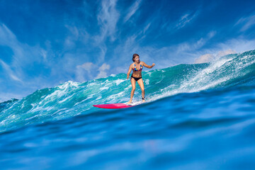 Female surfer on a blue wave at sunny day